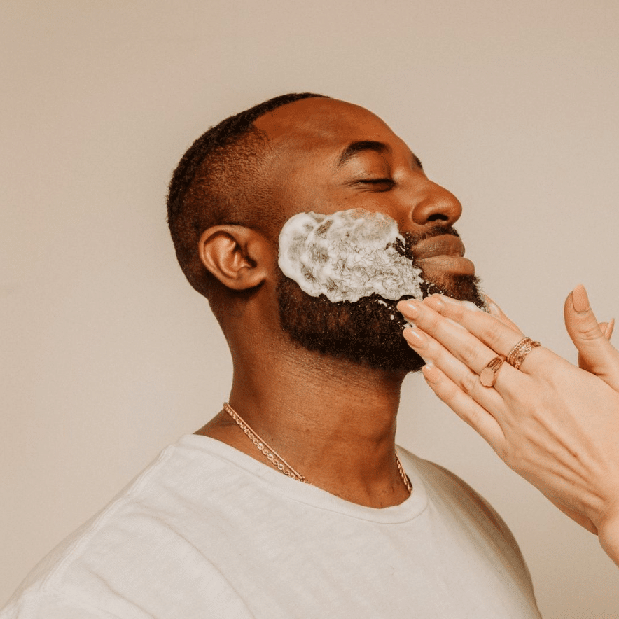 Man with mustache smiling with closed eyes having a facial wash