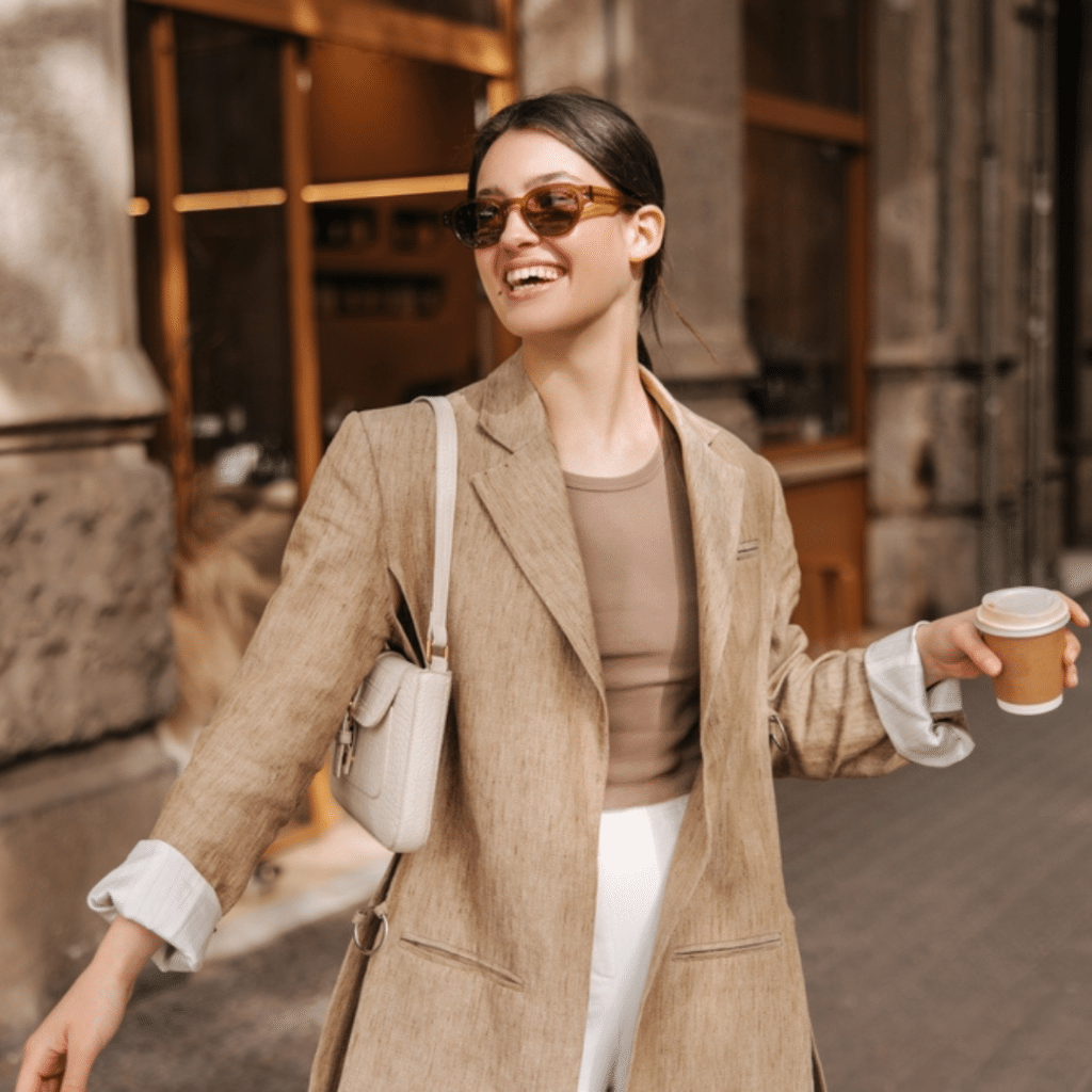 Woman with shades dressed in brown aesthetic clothes holding a cup of coffee
