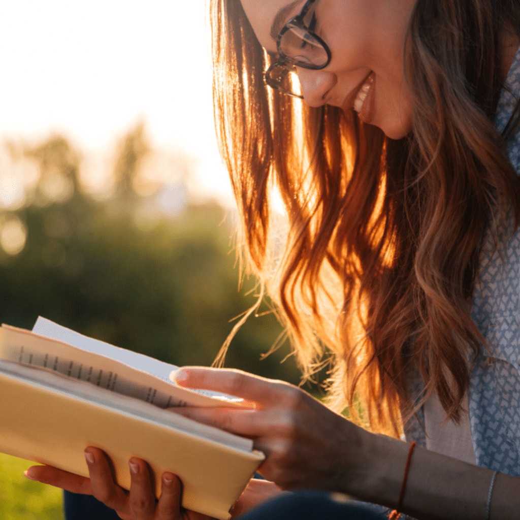 Woman with long hair reading a book with sunset background