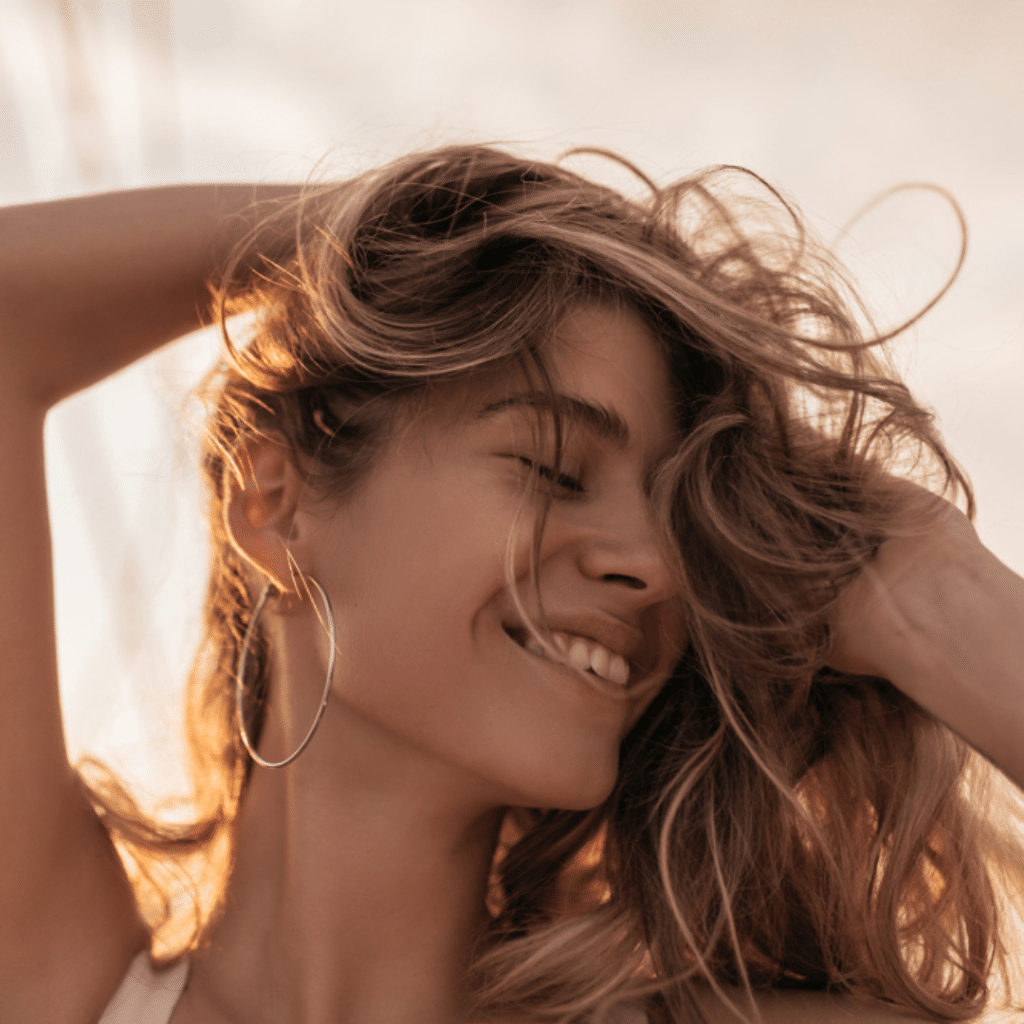 Woman smiling looking sidewards touching her hair