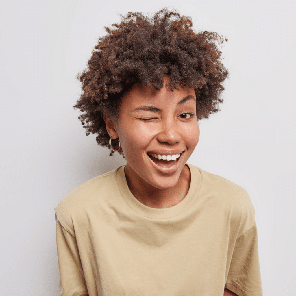 Woman with short curly hair smiling and winking